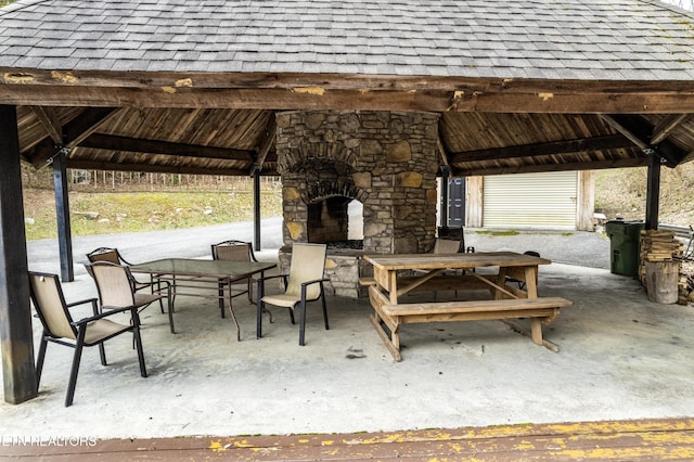 view of patio featuring a gazebo, an outdoor stone fireplace, and outdoor dining space