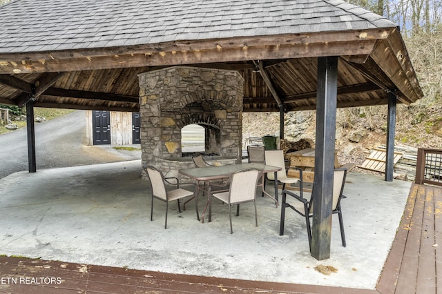 view of patio with outdoor dining space, a gazebo, and an outdoor stone fireplace