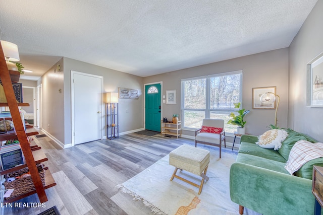 living room featuring a textured ceiling, baseboards, and wood finished floors