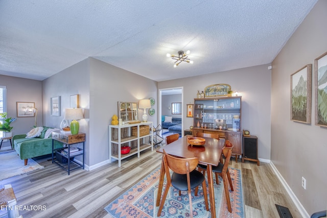 dining room featuring visible vents, a textured ceiling, and light wood-style flooring