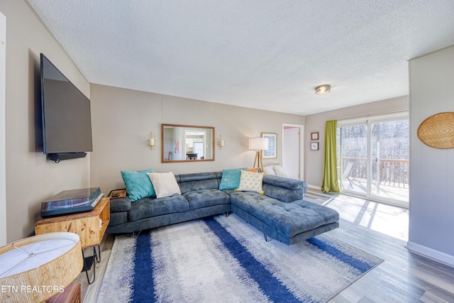 living area with a textured ceiling, baseboards, and wood finished floors