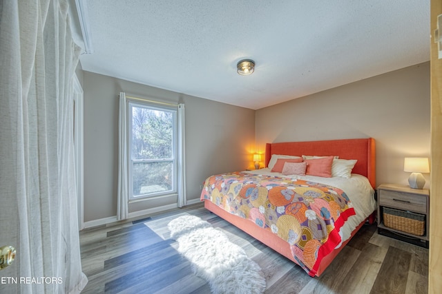 bedroom with visible vents, baseboards, a textured ceiling, and wood finished floors