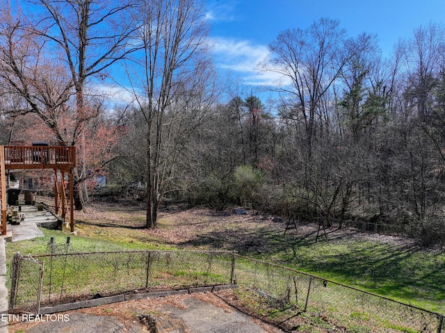 view of yard with a wooded view, a wooden deck, and fence