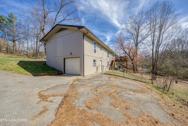 view of home's exterior featuring stairs, aphalt driveway, and fence