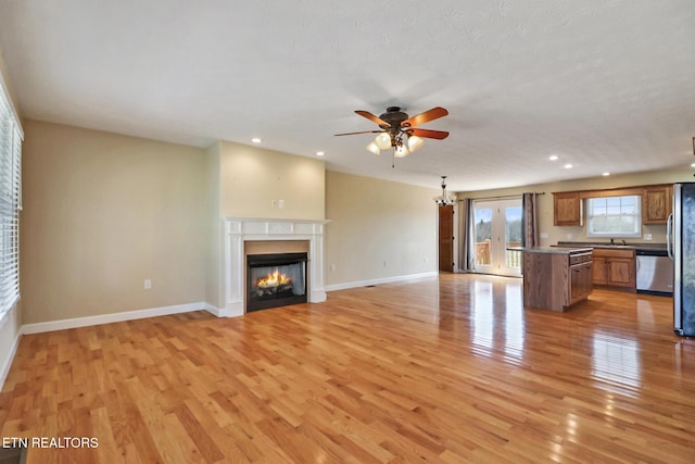 unfurnished living room featuring a glass covered fireplace, light wood-style flooring, and baseboards