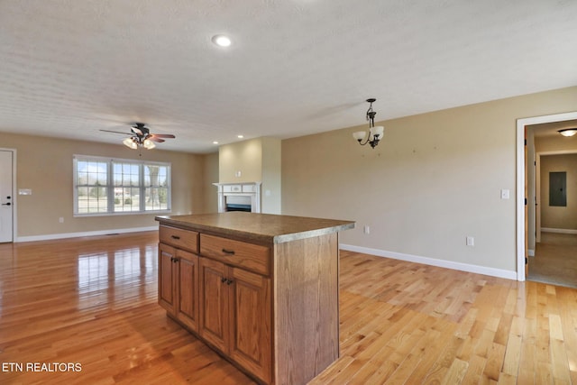 kitchen with open floor plan, electric panel, light wood-style flooring, a fireplace, and brown cabinetry