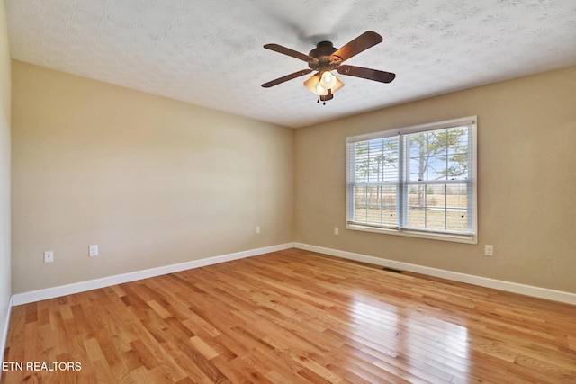 empty room with visible vents, baseboards, ceiling fan, light wood-style floors, and a textured ceiling