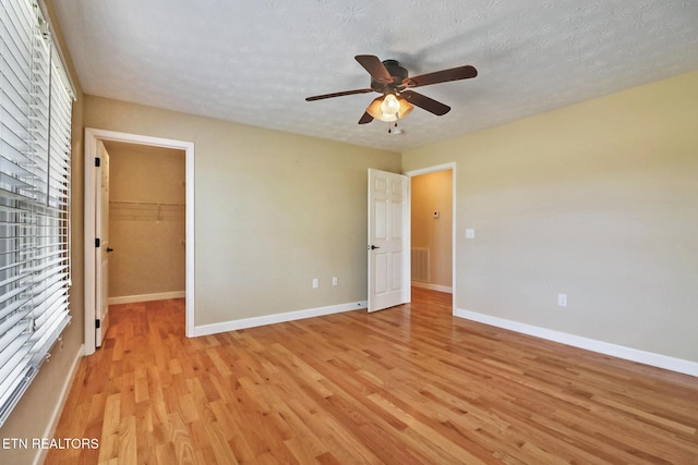 unfurnished bedroom featuring visible vents, baseboards, light wood finished floors, and a textured ceiling