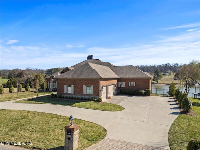 view of front of property featuring curved driveway, a front yard, a shingled roof, a garage, and brick siding