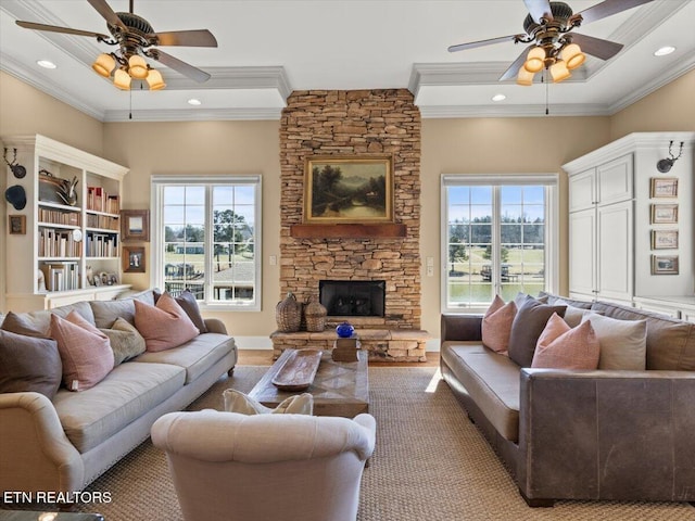 living room featuring plenty of natural light, a fireplace, a ceiling fan, and ornamental molding