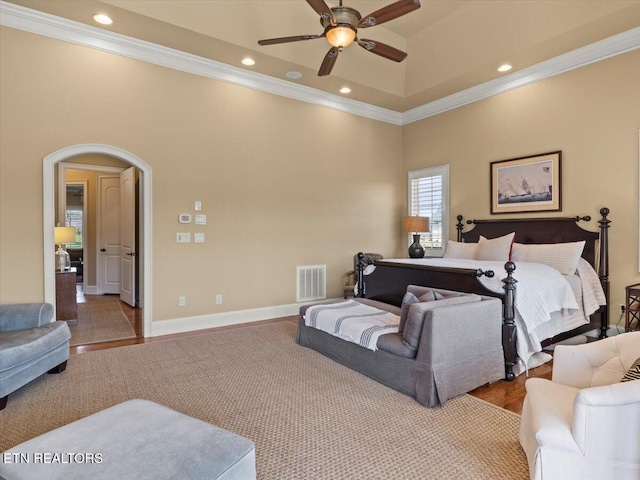 bedroom featuring visible vents, arched walkways, wood finished floors, and crown molding