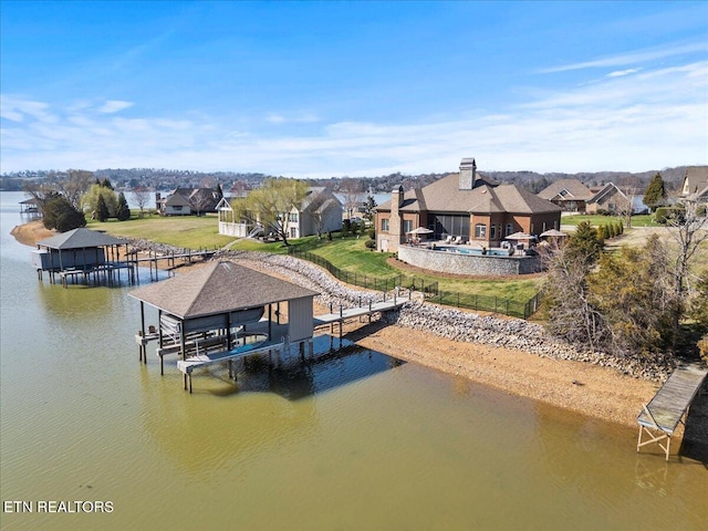 view of dock with a residential view, a water view, boat lift, and a yard