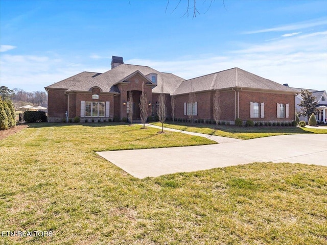 view of front of home featuring a front yard, brick siding, and a chimney