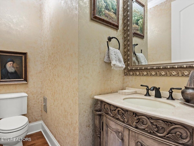 bathroom featuring toilet, vanity, baseboards, and wood finished floors