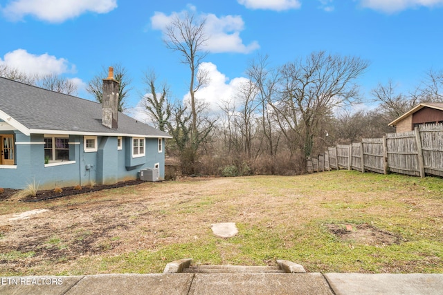 view of yard with central air condition unit and fence