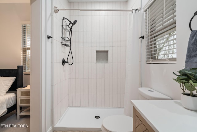 bathroom featuring a tile shower, plenty of natural light, toilet, and vanity