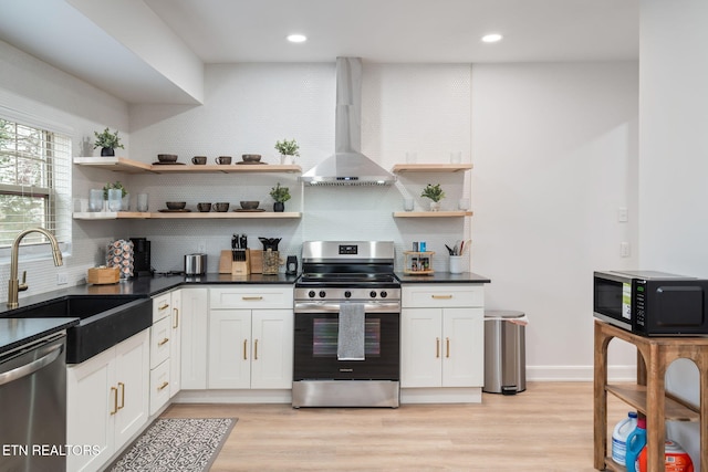 kitchen with a sink, open shelves, dark countertops, appliances with stainless steel finishes, and wall chimney range hood