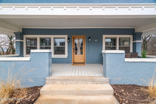 property entrance with stucco siding and a porch