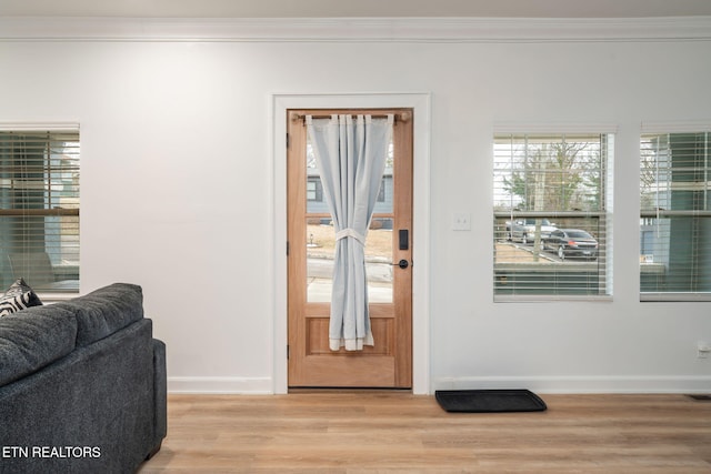 doorway with baseboards, light wood-style floors, and ornamental molding