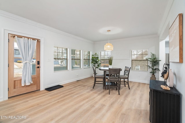 dining area featuring baseboards, light wood-style floors, and crown molding