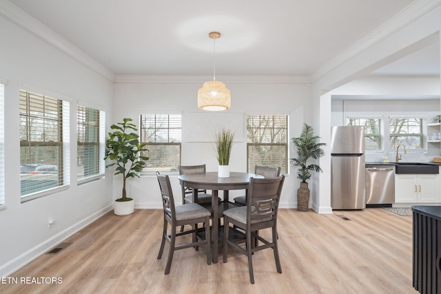 dining room featuring crown molding, baseboards, light wood-type flooring, and visible vents