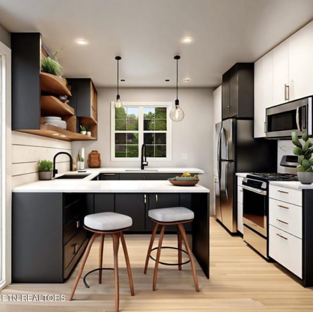 kitchen with a breakfast bar, a sink, open shelves, appliances with stainless steel finishes, and light countertops