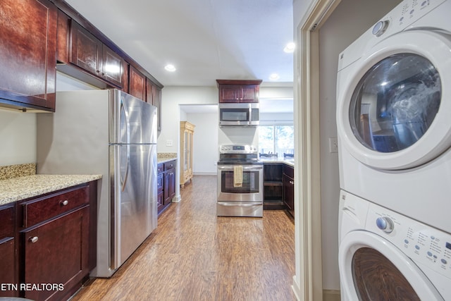 laundry room featuring stacked washer / dryer, recessed lighting, laundry area, and light wood-type flooring