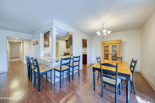 dining area with a notable chandelier, baseboards, and dark wood-style flooring