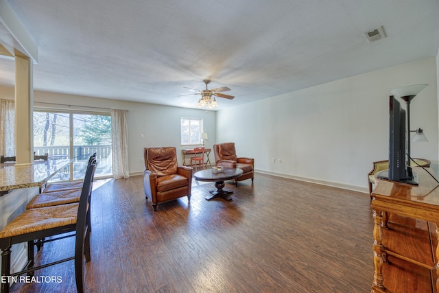 living room featuring hardwood / wood-style flooring, a ceiling fan, baseboards, and visible vents