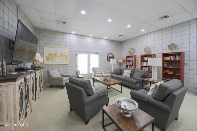 living area featuring light carpet, visible vents, recessed lighting, and tile walls