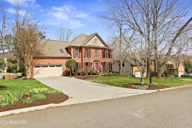 colonial house with brick siding, a shingled roof, fence, concrete driveway, and a front yard