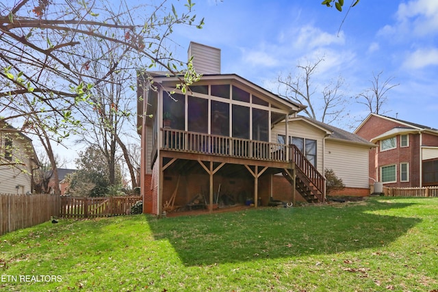 rear view of property with stairway, a sunroom, a chimney, fence private yard, and a lawn