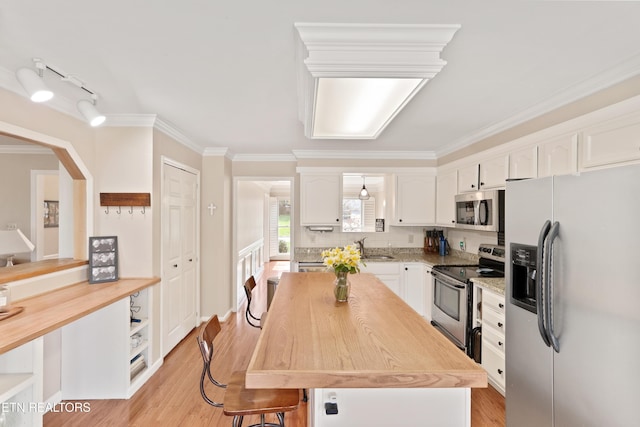 kitchen featuring light wood finished floors, white cabinets, stainless steel appliances, wood counters, and a sink