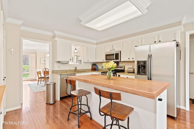 kitchen with a breakfast bar area, light wood-style flooring, appliances with stainless steel finishes, white cabinetry, and a sink