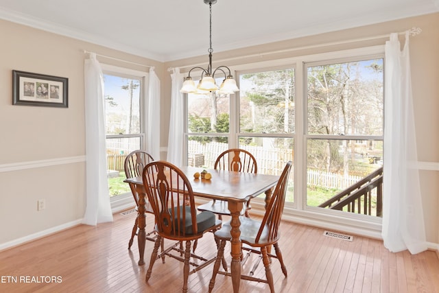 dining room featuring visible vents, a chandelier, crown molding, and light wood finished floors