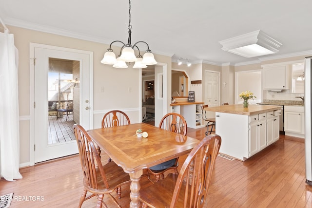 dining room with light wood-type flooring, a chandelier, and ornamental molding