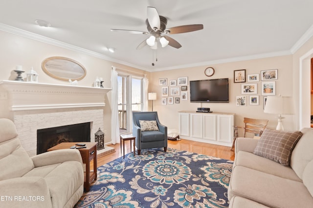 living area with light wood-style flooring, a brick fireplace, a ceiling fan, and ornamental molding