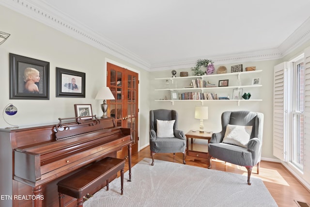 living area with visible vents, ornamental molding, and wood finished floors