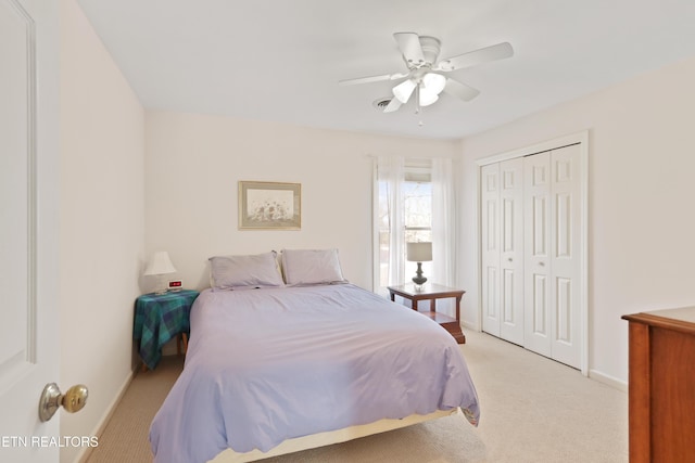 bedroom featuring a closet, light colored carpet, baseboards, and ceiling fan