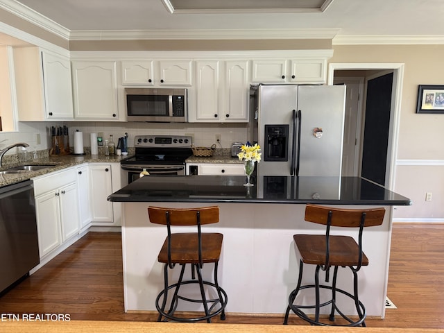 kitchen featuring a sink, crown molding, wood finished floors, and stainless steel appliances