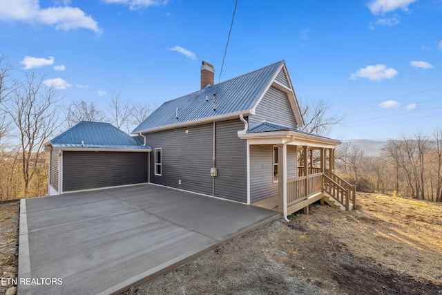 view of property exterior with a detached garage, a chimney, and metal roof