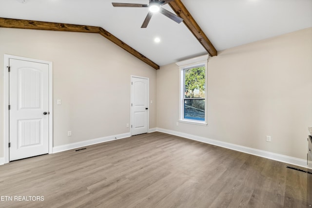 empty room with baseboards, wood finished floors, ceiling fan, and vaulted ceiling with beams