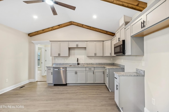 kitchen featuring light wood-style flooring, a ceiling fan, appliances with stainless steel finishes, and a sink