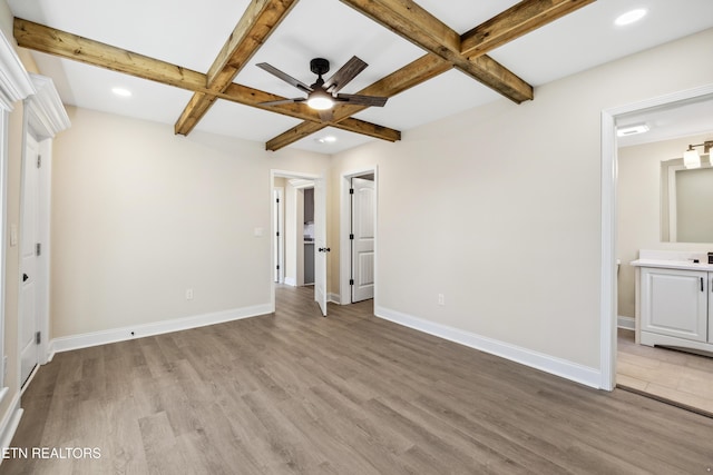 unfurnished bedroom featuring light wood finished floors, beamed ceiling, and baseboards