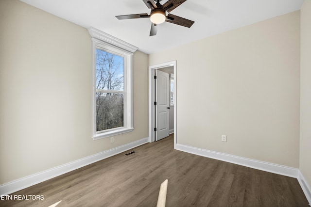 spare room with baseboards, wood finished floors, and a ceiling fan