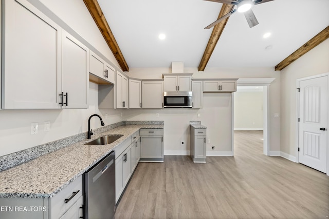 kitchen with light stone countertops, a ceiling fan, a sink, light wood-style floors, and appliances with stainless steel finishes