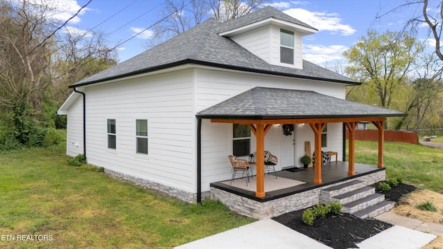 view of side of property featuring a lawn and roof with shingles
