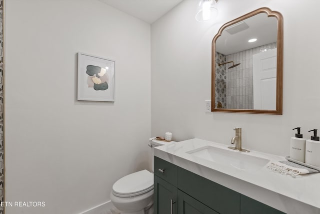bathroom featuring toilet, vanity, baseboards, and a tile shower