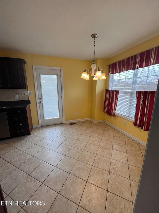 unfurnished dining area with light tile patterned floors, visible vents, baseboards, and a notable chandelier