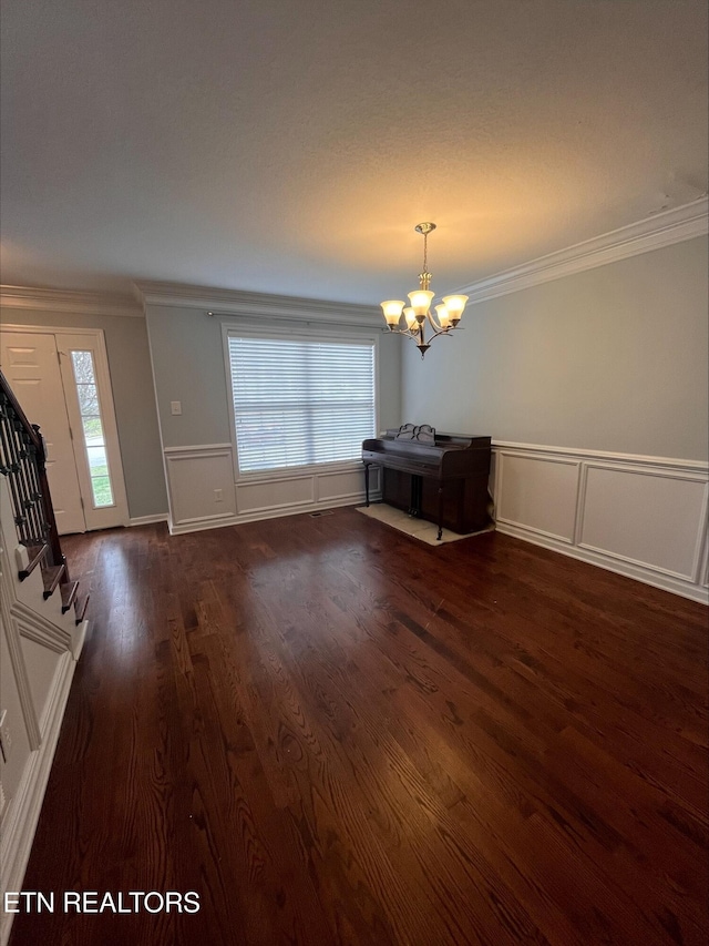 interior space featuring ornamental molding, wood finished floors, stairway, an inviting chandelier, and wainscoting